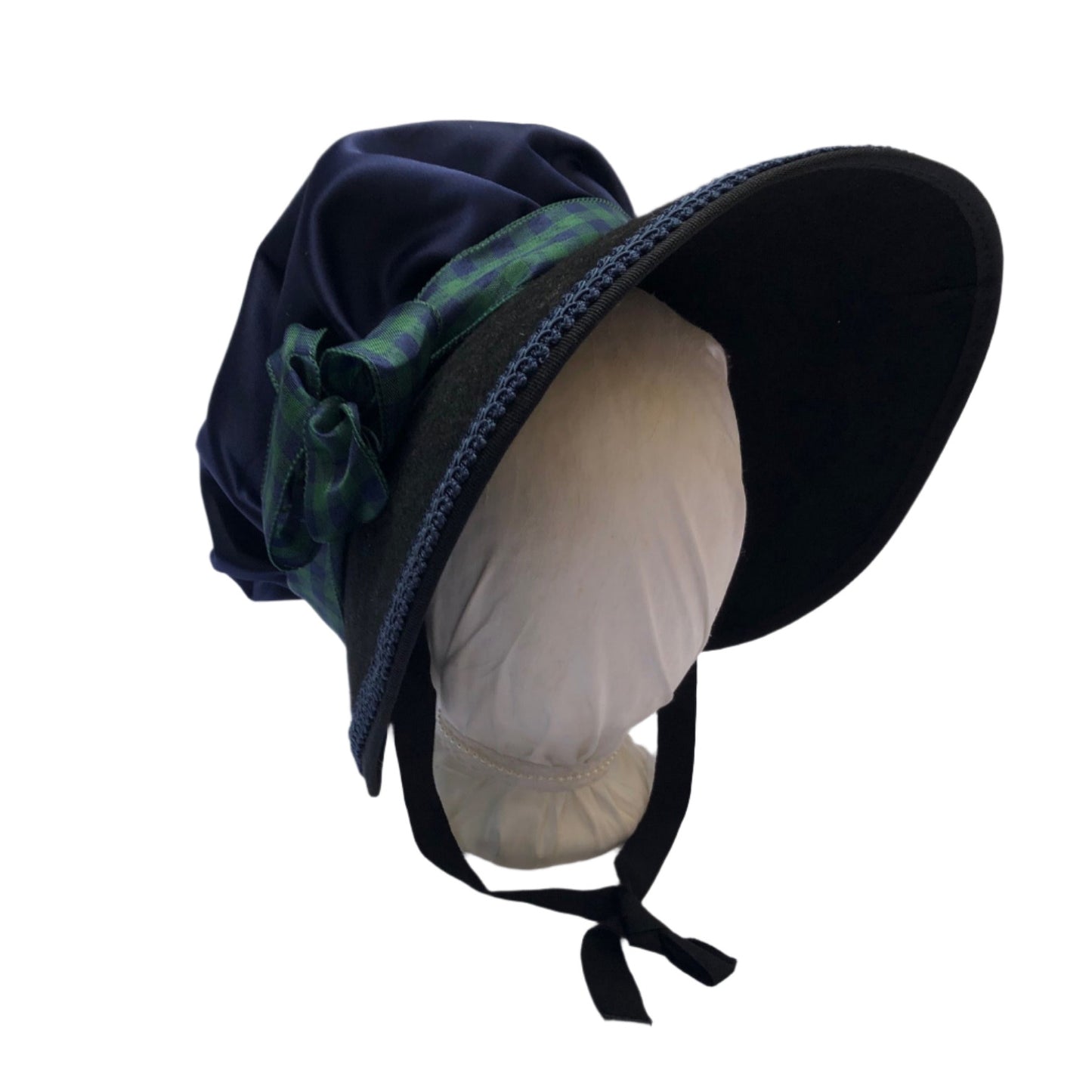 Black victorian style bonnet with blue satin crown, blue gimp cord decoration on brim and green and blue plaid ribbon.