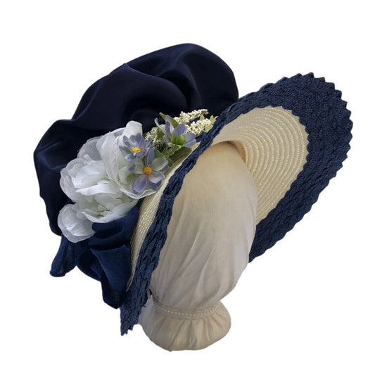 Packable regency style bonnet in ivory and dark blue with a white peony, and blue wild flowers.
